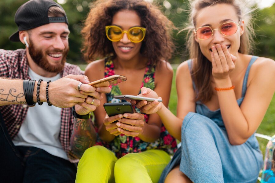 A group of diverse friends laughing and chatting together on a park bench, using the UpSwap app on their phones.